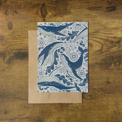 Humpback whale illustration on a patterned card against a brown kraft paper envelope.