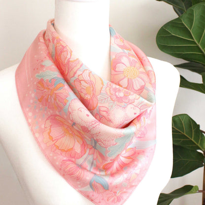 Pink silk twill scarf featuring illustrated bunnies and floral designs, perfect for accessories and decor.