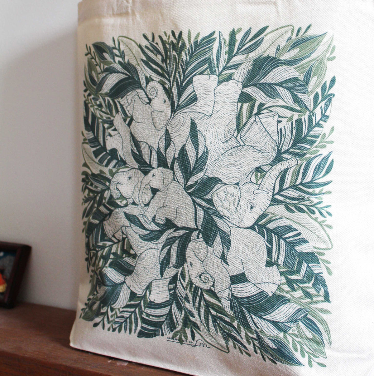 Elephant 'Siesta' canvas tote bag featuring illustrated elephants surrounded by greenery, perfect for everyday use.