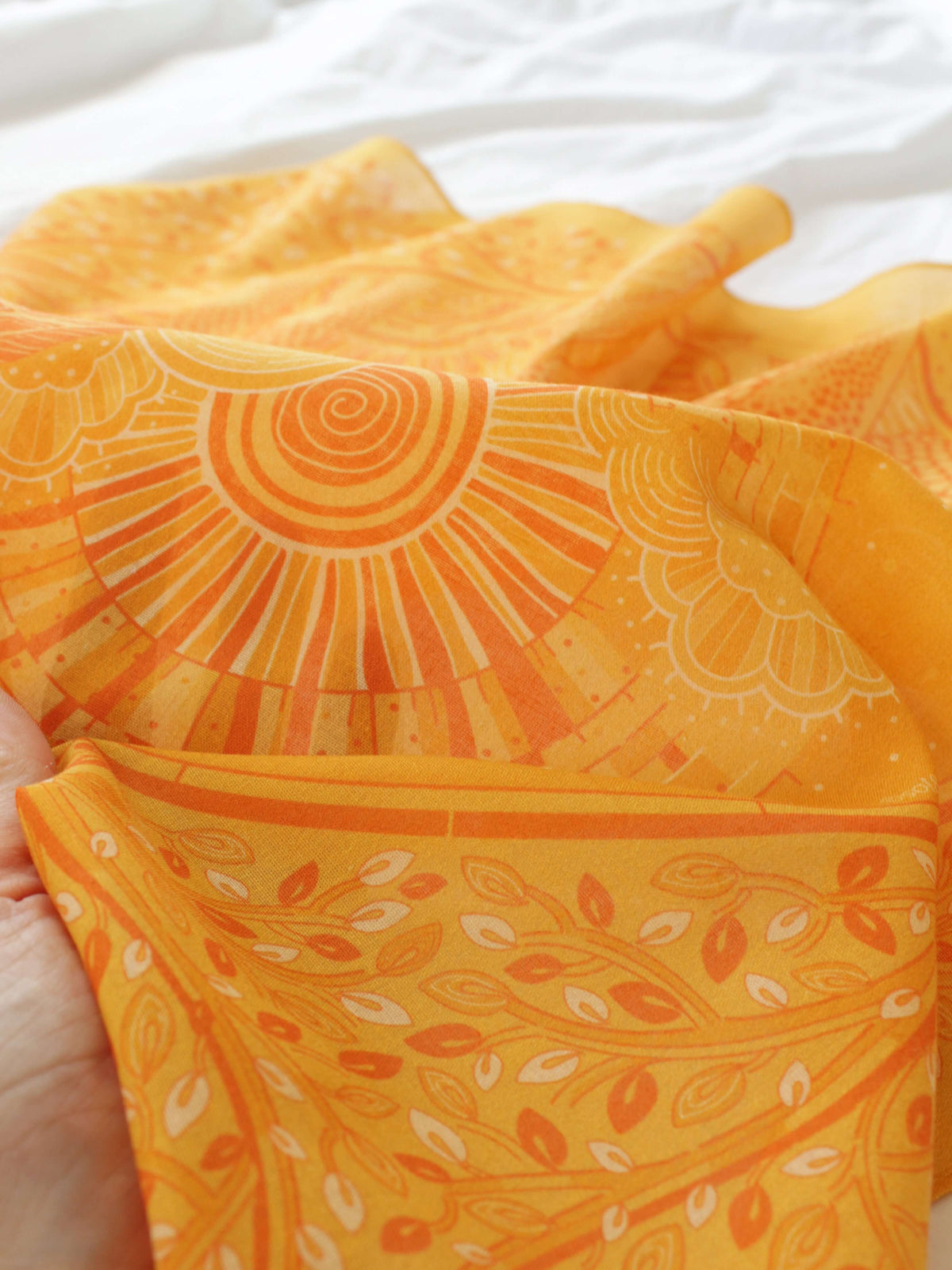 Close-up of a soft golden yellow bandana featuring intricate designs, perfect for accessorizing hair or bags.