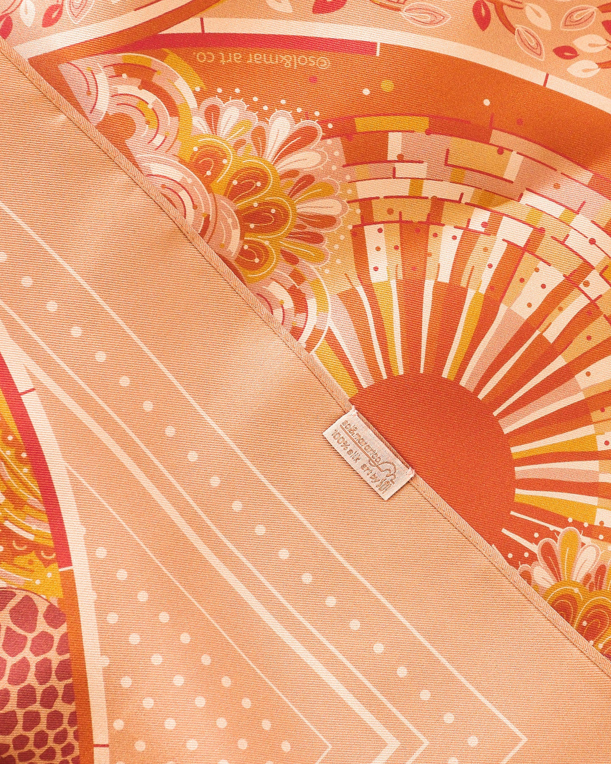 Decorative product with intricate patterns and a brand logo on an orange background