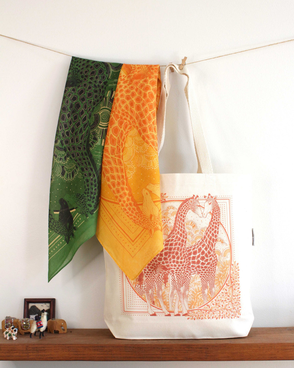 Giraffe art canvas tote bag displayed with colorful scarves on a wooden shelf.