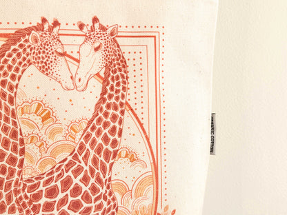Giraffe art illustration on organic cotton canvas tote bag, featuring two giraffes in warm colors.