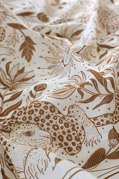 Close-up of off-white cotton scarf featuring leopard and floral line art design.