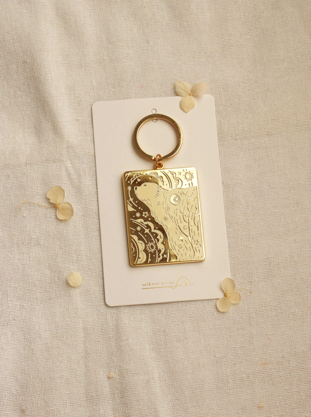 Gold-plated polar bear enamel keychain on display card against a neutral background.