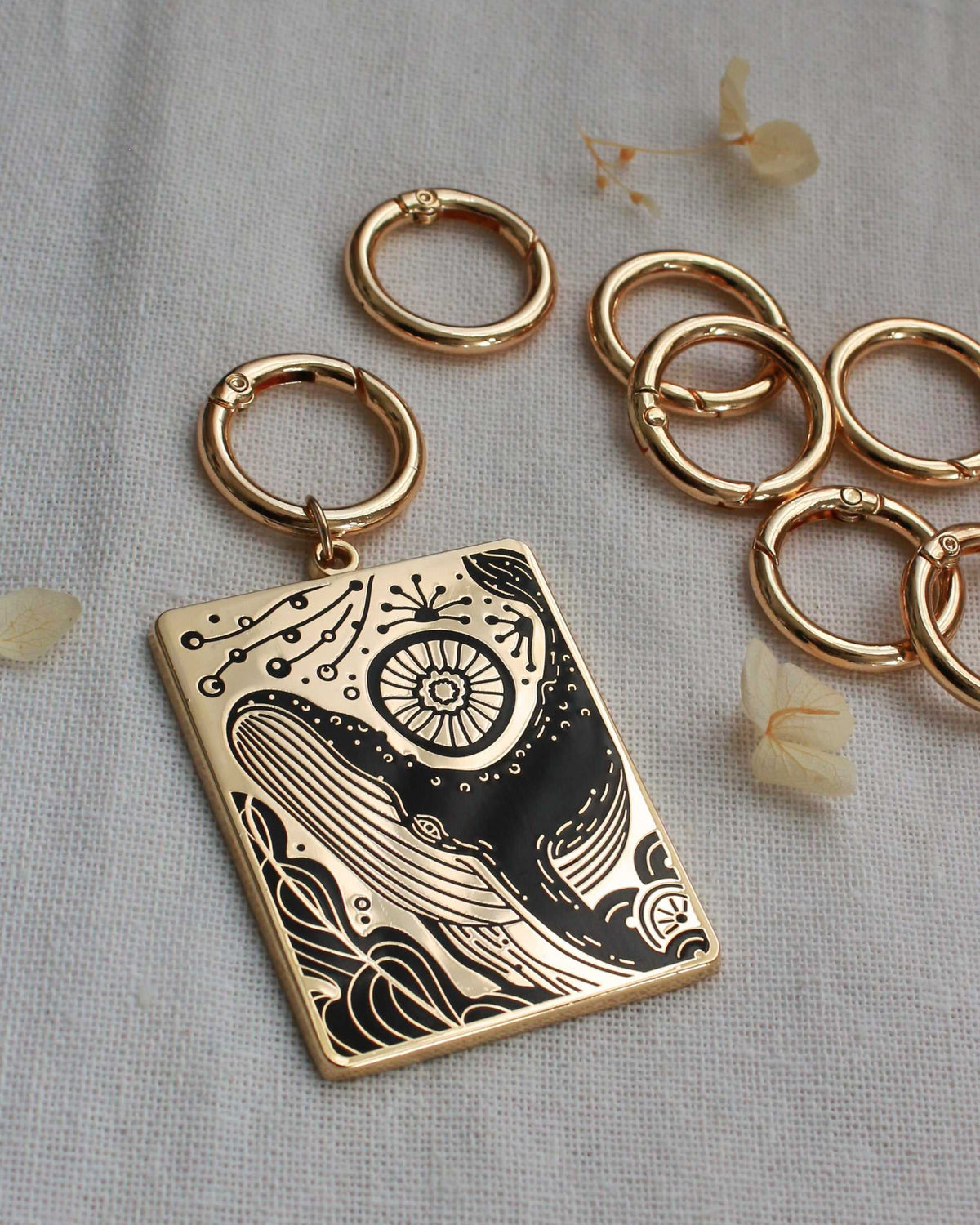 Humpback whale and ocean enamel keychain with gold plating and intricate design, displayed with metal rings.