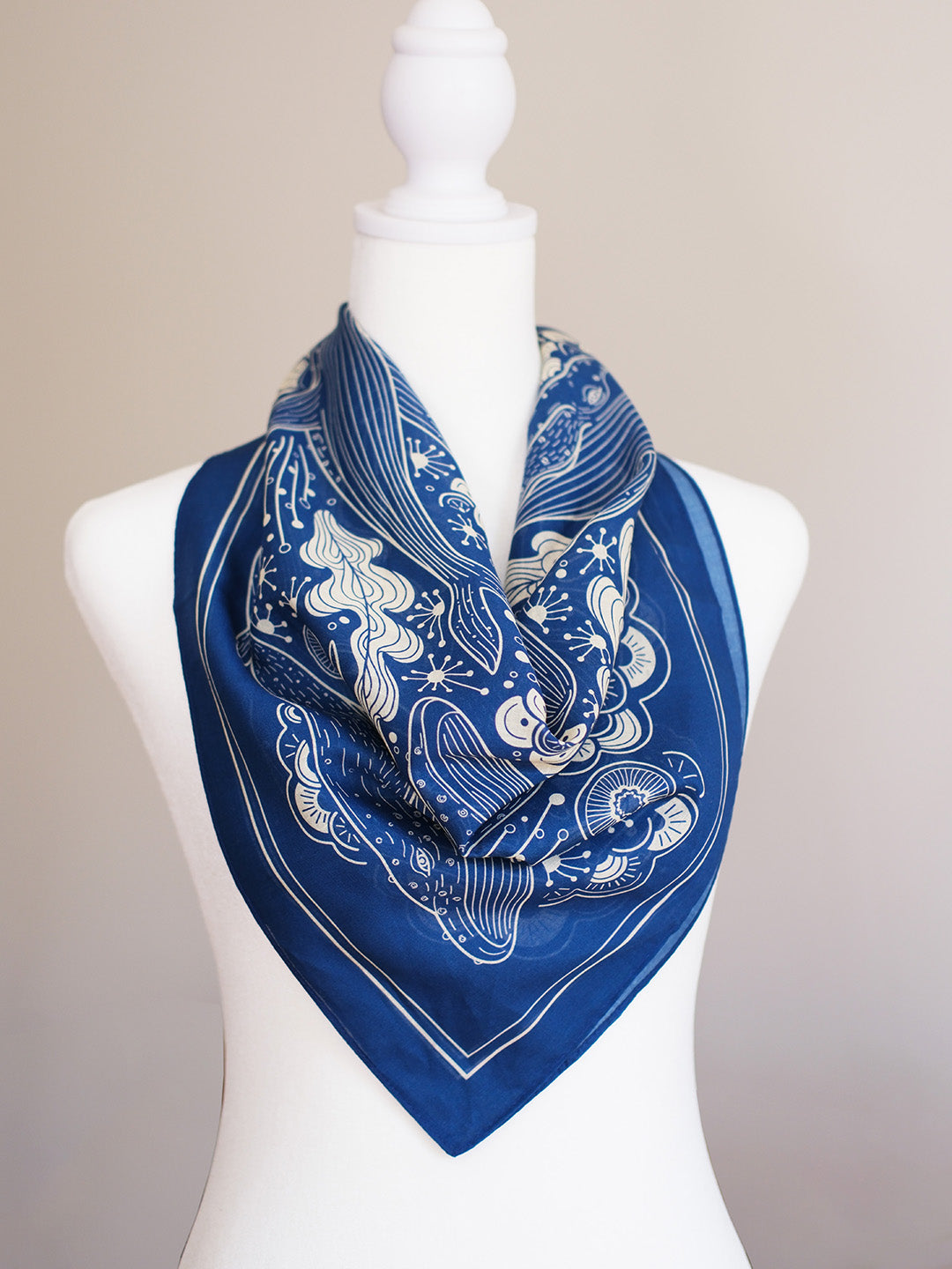 Navy whale and ocean bandana scarf displayed on a mannequin, showcasing intricate design and soft cotton fabric.