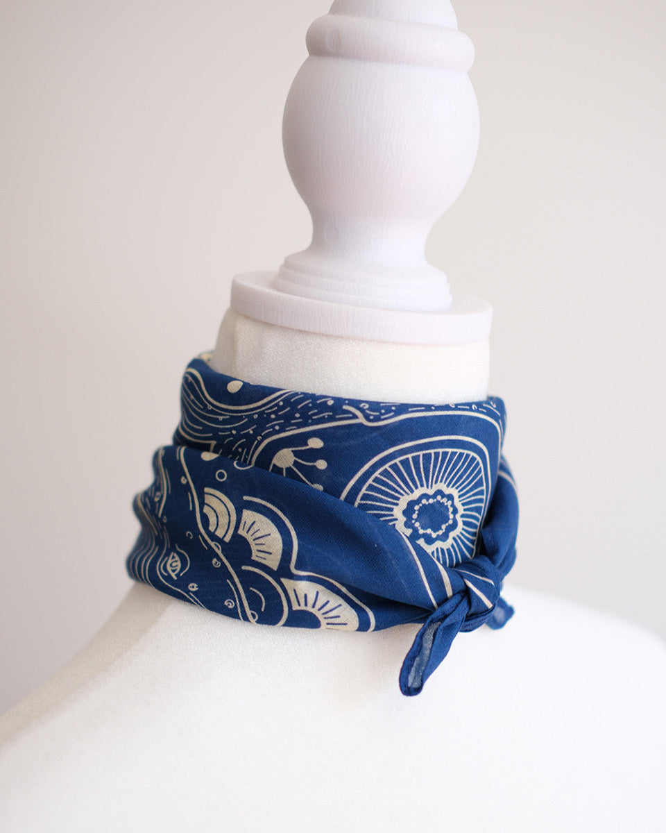 Navy whale and ocean bandana scarf tied around a model's neck, showcasing artistic design and soft cotton fabric.