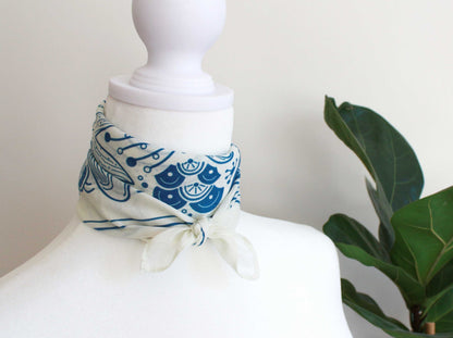 Whale and Ocean bandana scarf displayed on a mannequin, featuring intricate blue patterns against an off-white background.