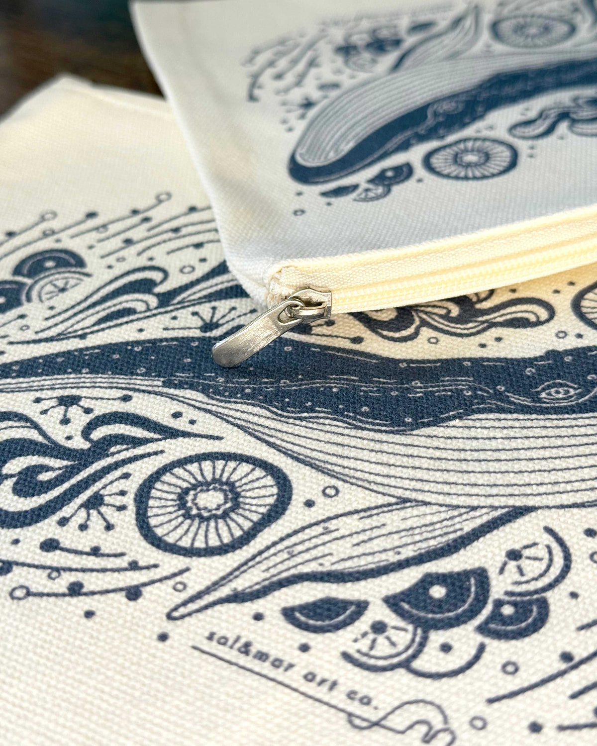 Close-up of whale design on cotton canvas zipper pouch, featuring intricate ocean-themed illustrations.