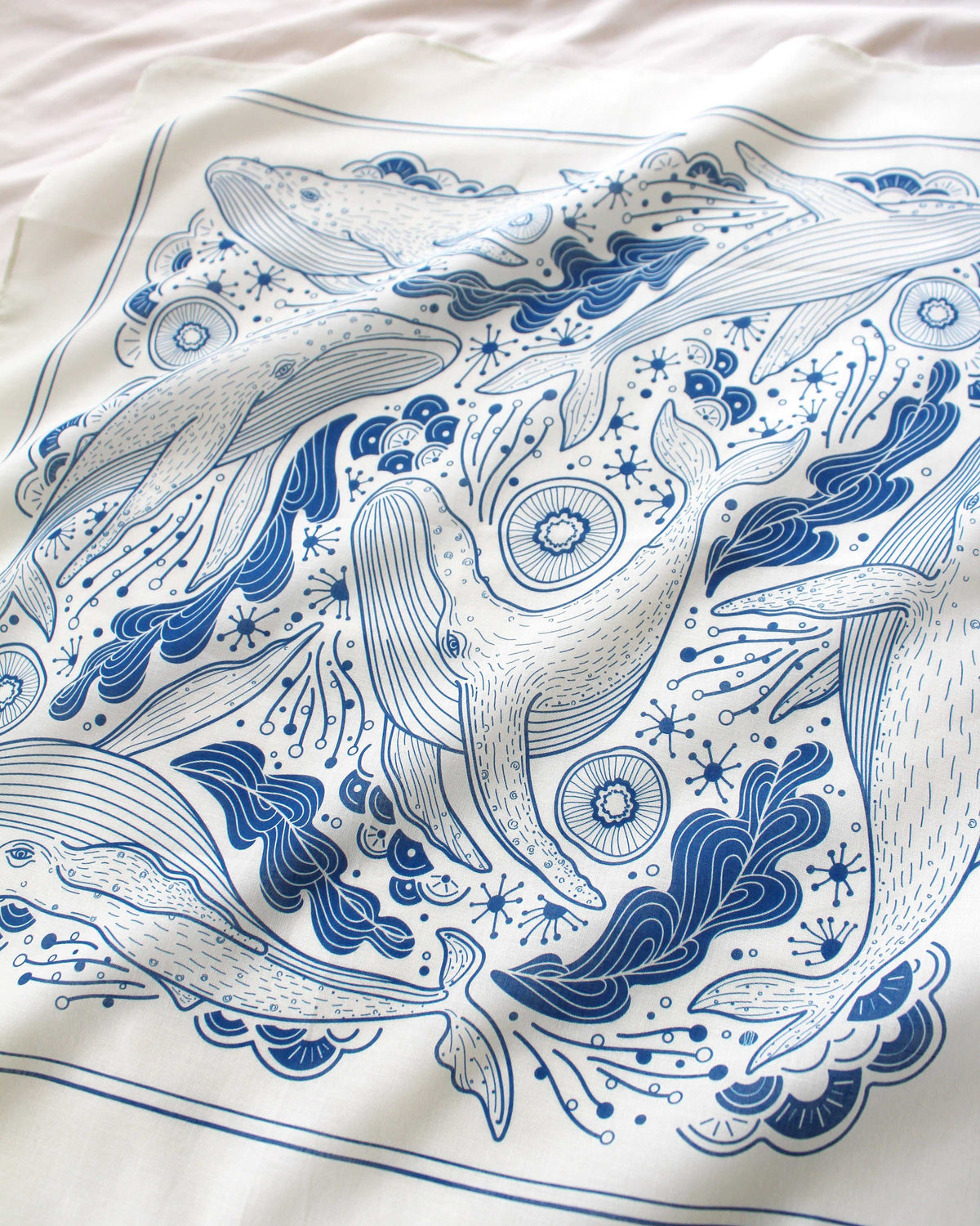 Whale and ocean art on off-white bandana scarf, featuring humpback whales and ocean motifs in blue design.