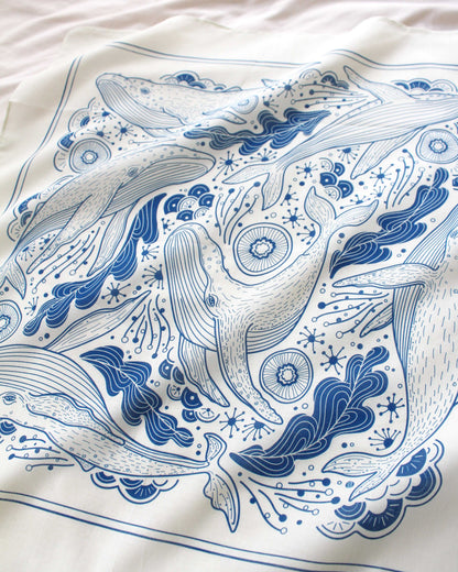 Whale and ocean art on off-white bandana scarf, featuring humpback whales and ocean motifs in blue design.