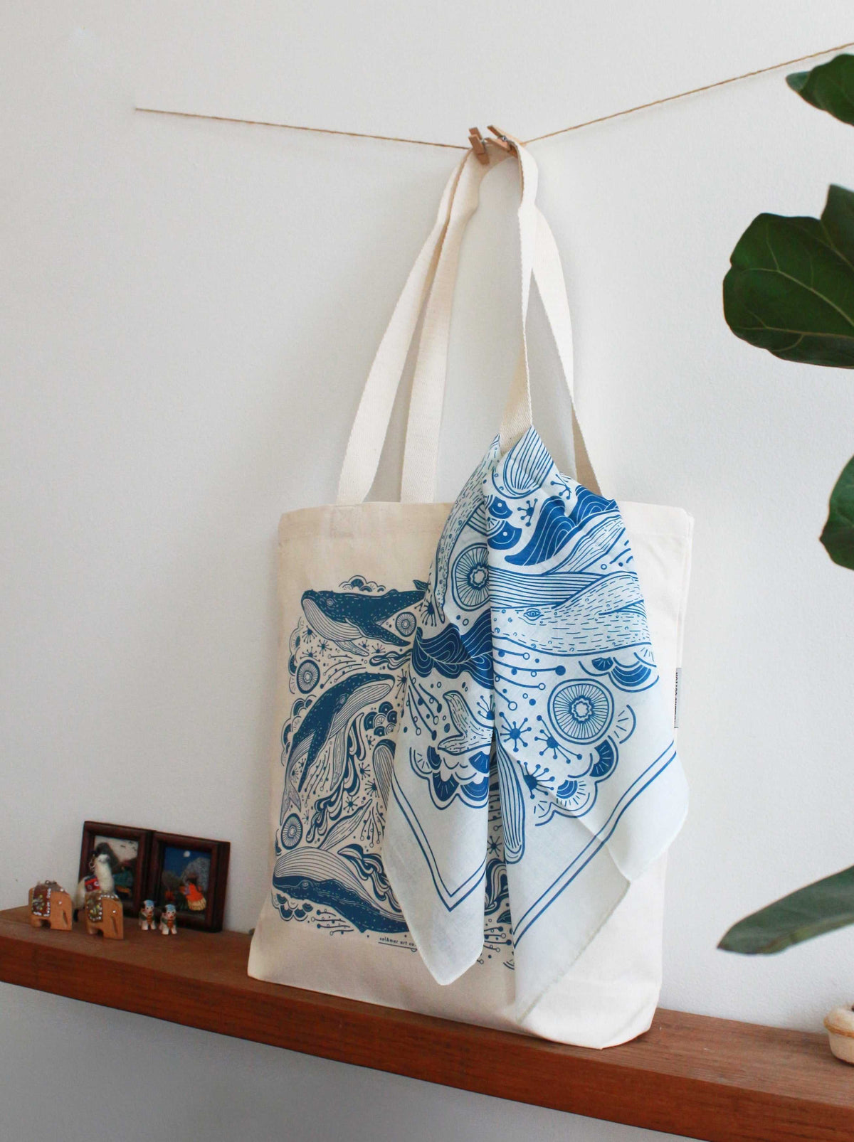Off-white tote bag with blue ocean design and bandana scarf displayed on a shelf, perfect for stylish summer accessories.