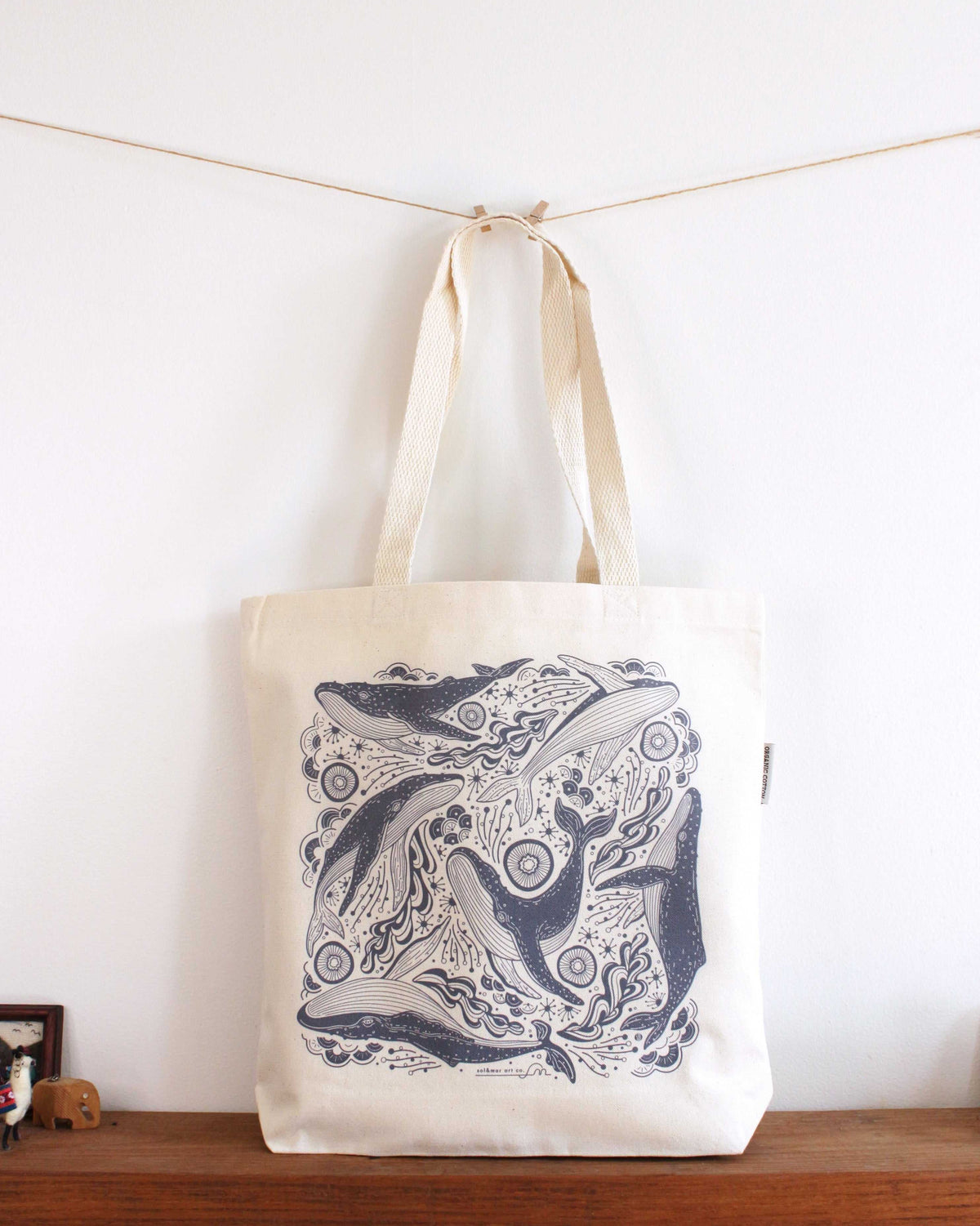 Whale and ocean illustrated canvas tote bag on display with sturdy handles, perfect for everyday use.