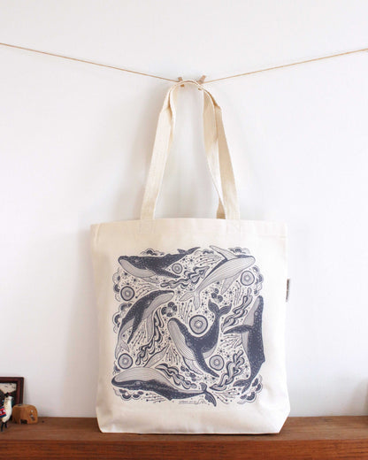 Whale and ocean illustrated canvas tote bag on display with sturdy handles, perfect for everyday use.