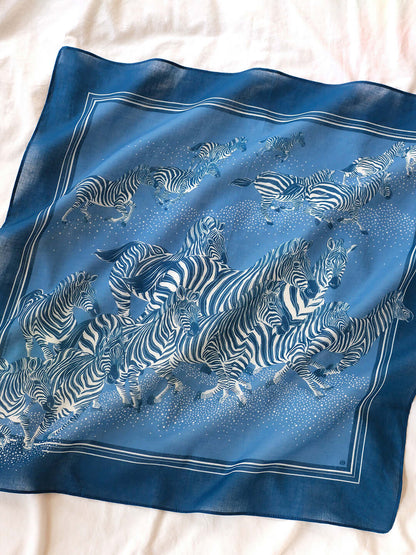 Blue bandana scarf featuring a herd of zebras running, perfect for hair, accessories, or decor.