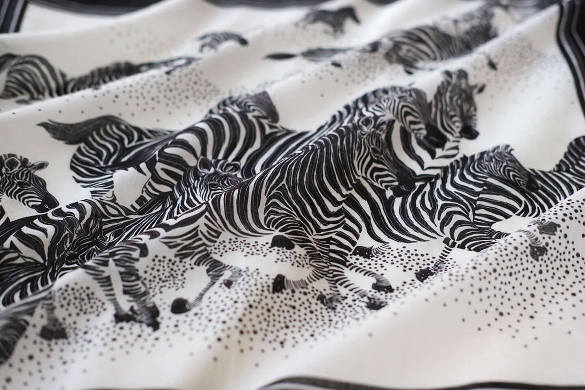 Black and white bandana scarf featuring a herd of zebras running across a soft cotton fabric.