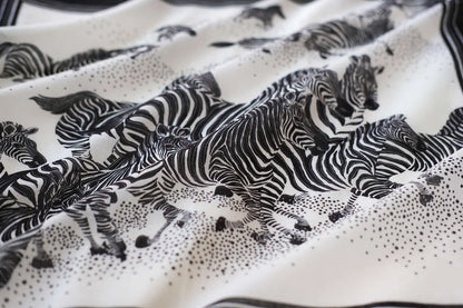 Black and white bandana scarf featuring a herd of zebras running across a soft cotton fabric.
