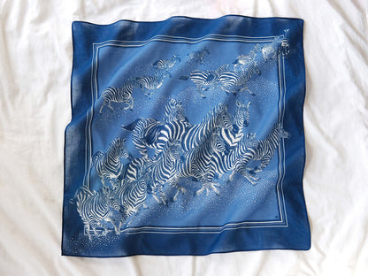 Blue zebra bandana scarf featuring a herd of zebras, 22x22 inches, soft cotton for versatile styling and year-round wear.