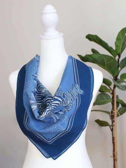 Blue zebra bandana scarf featuring a herd of zebras, 22x22 inches, soft cotton for versatile styling and year-round wear.