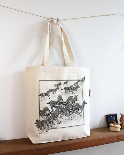 Zebra, 'New Beginning' canvas tote bag featuring artwork of a herd of zebras in motion on a natural canvas background.