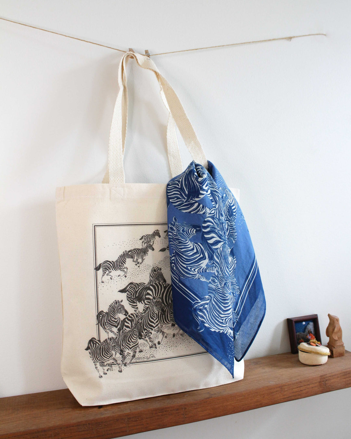 Zebra art canvas tote bag with blue patterned scarf, displayed on a wooden shelf.