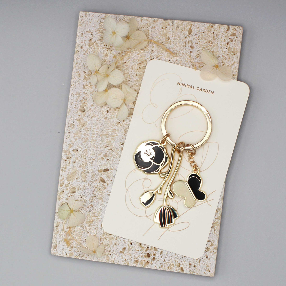 Black Minimal Garden Keychain on display card with floral charms and gold-plated hardware.