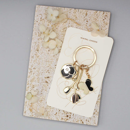 Black Minimal Garden Keychain on display card with floral charms and gold-plated hardware.