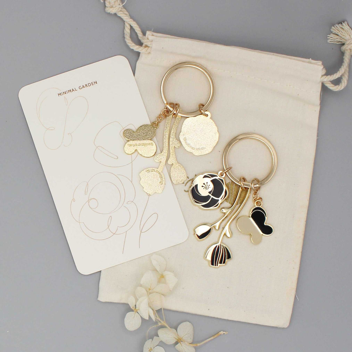 Minimal Garden Keychain featuring black flower and butterfly charms with gold plating on a display card.
