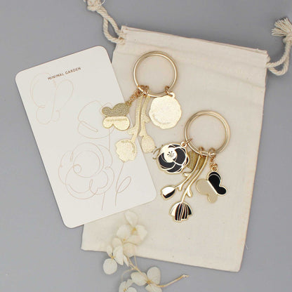 Minimal Garden Keychain featuring black flower and butterfly charms with gold plating on a display card.