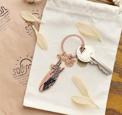 Whale Shark enamel keychain on a cloth bag with dried petals, promoting awareness of endangered species.