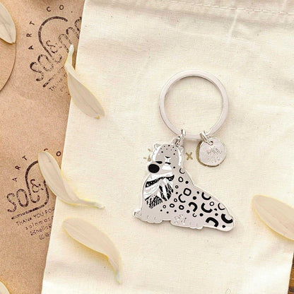 Snow Leopard enamel keychain featuring detailed art and habitat design, promoting wildlife conservation.
