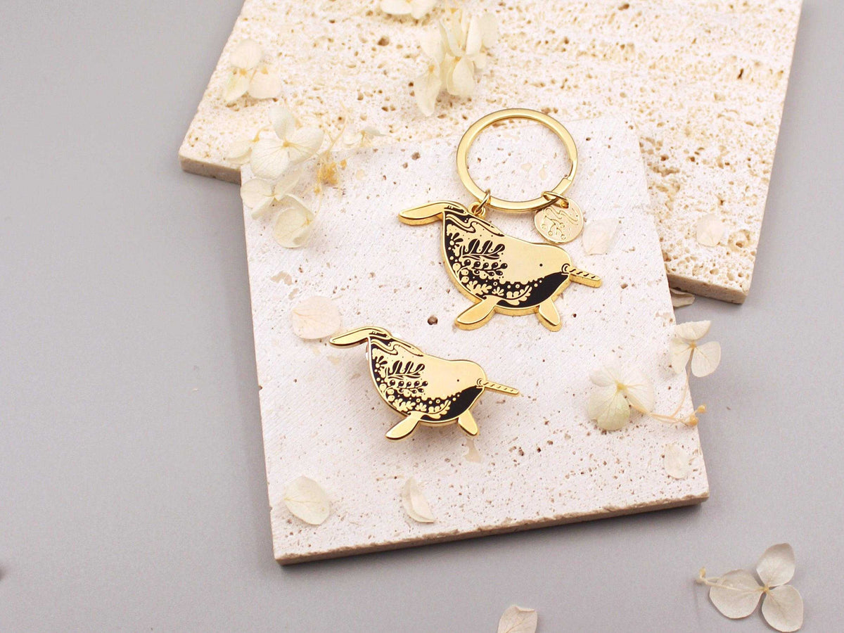 Narwhal enamel keychain with delicate line art and charm, promoting awareness for endangered animals.