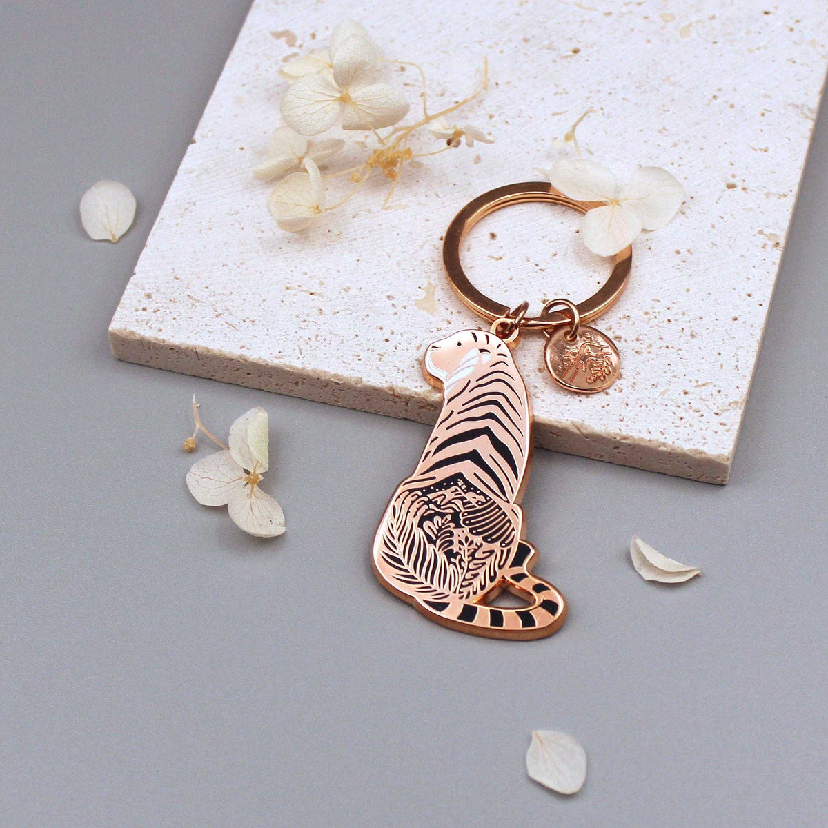 Sunda Tiger enamel keychain showcasing delicate habitat art, with an organic-shaped tag and floral accents.