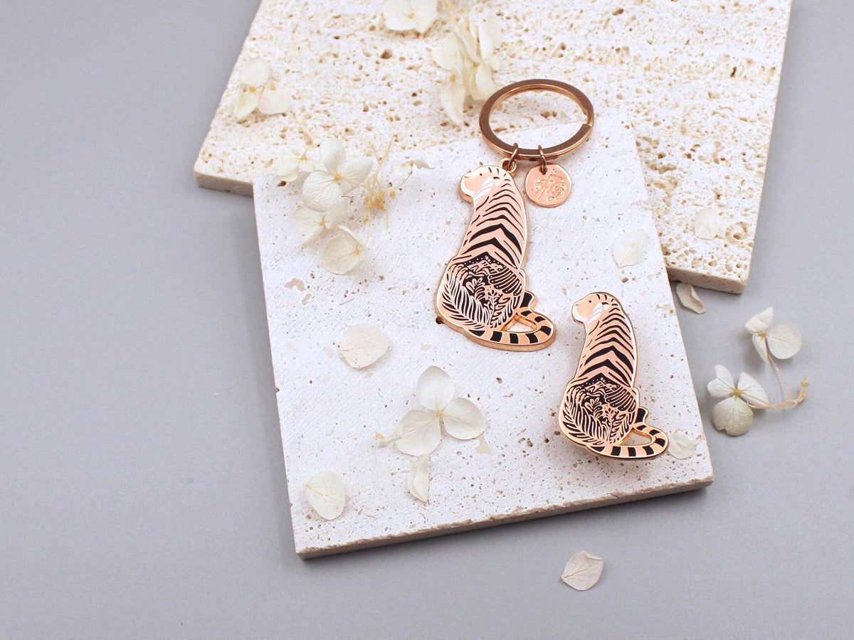 Sunda Tiger enamel keychain showcasing detailed art of its habitat on a textured background with decorative flowers.