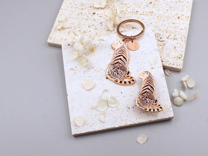 Sunda Tiger enamel keychain showcasing detailed art of its habitat on a textured background with decorative flowers.
