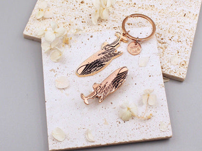 Whale Shark enamel keychain on a textured surface with floral accents, promoting endangered species awareness.